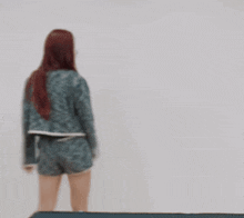 a woman with red hair is standing with her arms outstretched in front of a white wall .