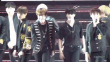 a group of young men are standing on a stage and dancing .