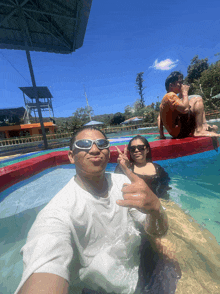 a man wearing sunglasses is taking a selfie in a pool with two other people
