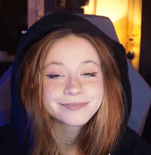 a girl with red hair wearing a black hoodie smiles for the camera