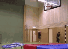 a person is doing a trick on a trampoline in front of a basketball hoop