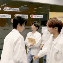 a group of young men are standing in front of a glass wall with a sign that says sina on it