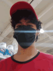 a man wearing a mask and a red hat looks at the camera