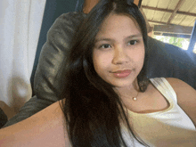 a woman with long hair is wearing a white tank top and pearl necklace