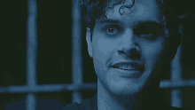 a close up of a man 's face in a dark room behind a fence .