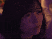 a close up of a woman 's face with purple light behind her