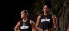 two women are standing next to each other in a dark room at night .