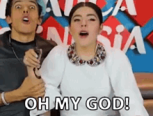 a man and a woman are sitting next to each other and the woman is saying oh my god !