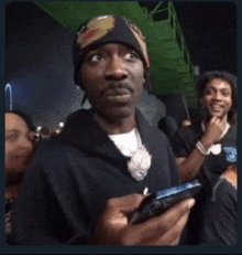 a man in a beanie is holding a cell phone .