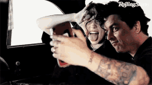 a man and a woman are taking a selfie in a car with their tongues out .