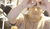 a man is making a heart shape with his hands while taking a selfie .