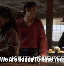 a woman in a red sweater stands in front of a bowl of fruit with the words we are happy to have you written below her