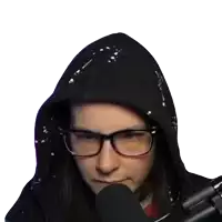 a woman wearing glasses and a black hoodie is sitting in front of a black microphone
