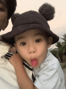 a little boy wearing a black hat with two pom poms on it