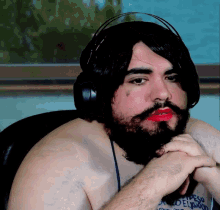 a man with a beard and red lipstick is wearing headphones and has a tattoo on his chest that says ' peso '