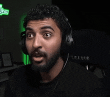 a man with a beard is wearing headphones in front of a leader chair .