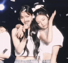 two girls are standing next to each other on a stage .