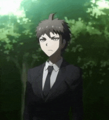 a young man in a suit and tie is standing in a forest .