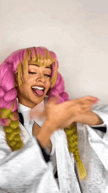 a woman in a pink wig and a white robe is making a funny face .