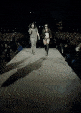 a man and a woman are walking down a runway