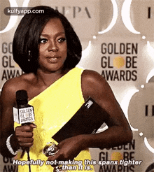 a woman in a yellow dress is holding a microphone and saying `` hopefully not making this spanx tighter than it is ''