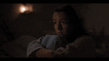 a woman is laying in a dark room with a light shining on her face