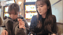 two young women are sitting at a table eating food
