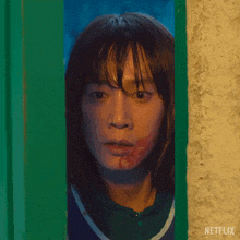 a woman with blood on her face is peeking out of a door .