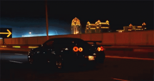 a car is driving down a highway at night with a sign in the background that says ksa