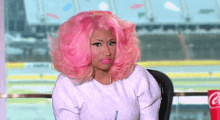 a woman with pink hair is sitting in front of a coca cola cup .