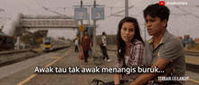 a man and a woman are sitting at a train station with the words awak tau tak awak menangis buruk
