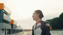a man in a motorcycle jacket is standing on a track .