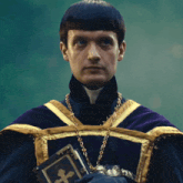 a man in a purple robe is holding a bible with a cross on it