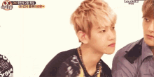 a young man with blonde hair is standing next to another young man with a shirt that says ' exo ' on it