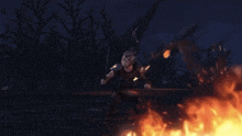 a person is standing in front of a fire in the dark