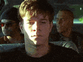 a man in a black shirt is sitting in a car with two other men