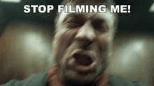 a blurry picture of a man screaming with the words stop filming me above him