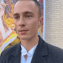 a close up of a man 's face in front of a painting .