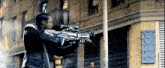 a man is holding a gun in front of a building .