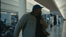a man wearing a blue hat and a jacket is walking through a mall