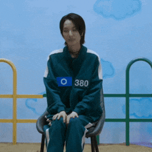 a woman is sitting in a chair with the number 380 on her shirt