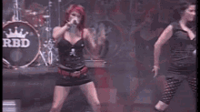 a woman is dancing on a stage while a man plays a guitar .