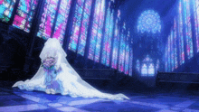 a woman in a bride 's dress holds a bouquet of flowers in front of a church with stained glass windows