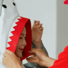 a woman wearing a shark costume is being helped by a man