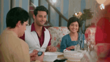 a group of people are sitting around a table with a bowl of food