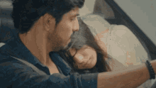 a man is driving a car with a woman laying on his lap