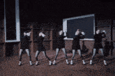 a group of women are dancing in front of a blackboard in a dark room
