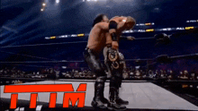two wrestlers in a wrestling ring with the letters t.i.t.m. in the corner