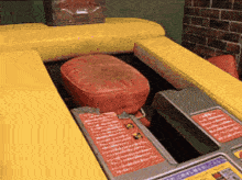 a red cushion is sitting on a yellow couch next to a machine