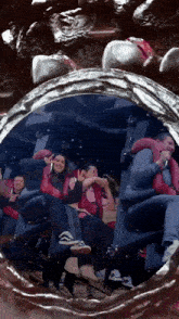 a group of people are riding a roller coaster and a woman is giving a peace sign .